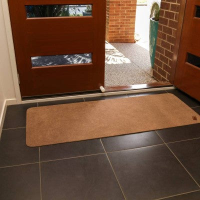 A rectangular, brown anti-slip floor mat placed on a wooden floor, near a white vehicle's entrance - Adaptive Equipment (Image 2).