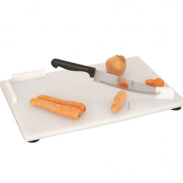 A white cutting board with a chef's knife on it, secured by suction cups. Carrots are also visible on the board, indicating its use for cutting food from Adaptive Equipment.